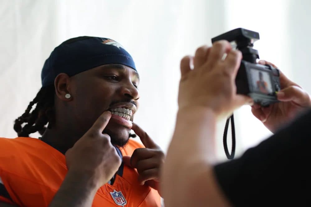 An NFL rookie in a team jersey having his photograph taken at a rookie event