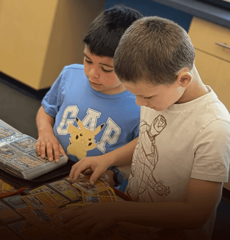 Children sorting and trading Pokémon cards together at a table