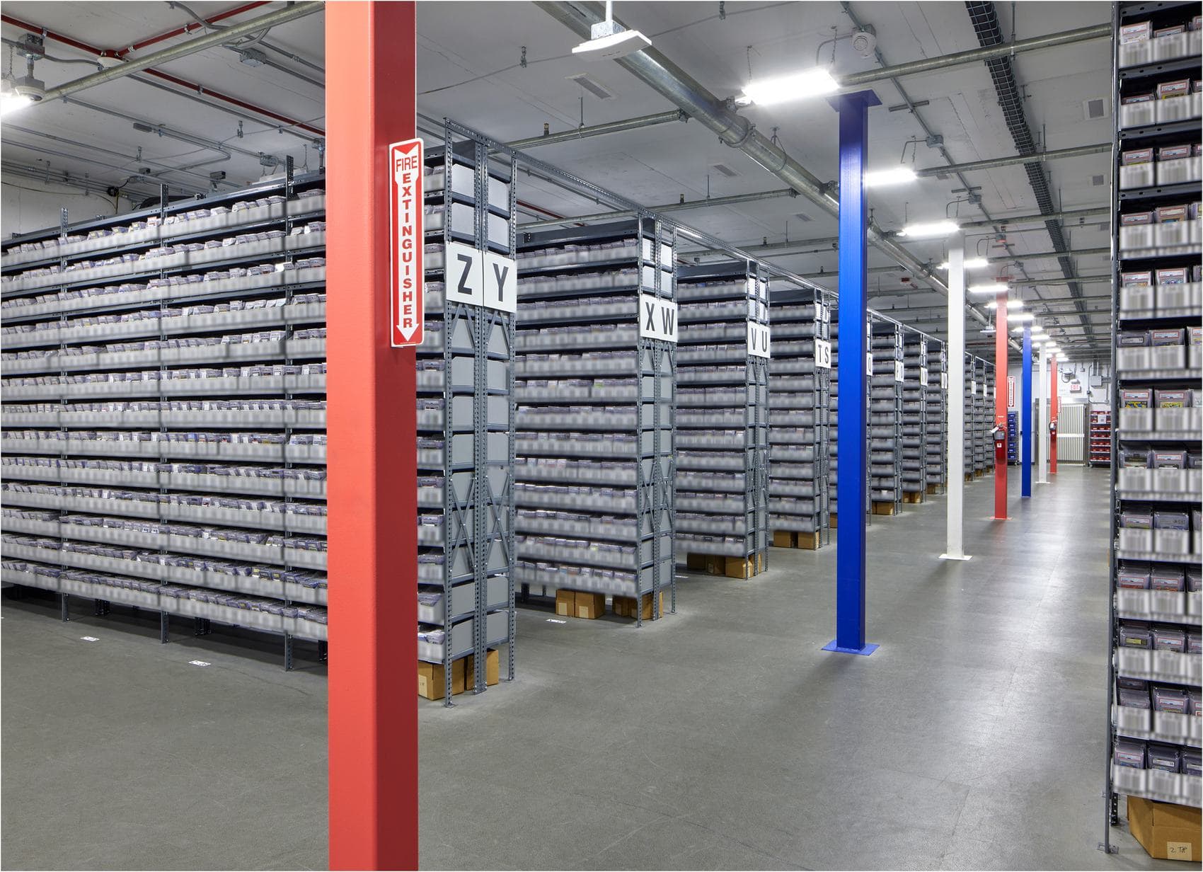Rows of industrial shelving stacked with boxed graded-card inventory